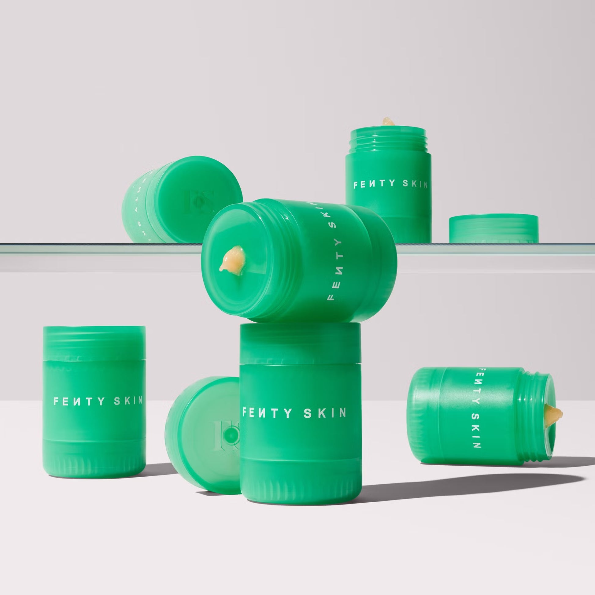 Green skincare containers with 'Fenty Skin' branding on a light gray background