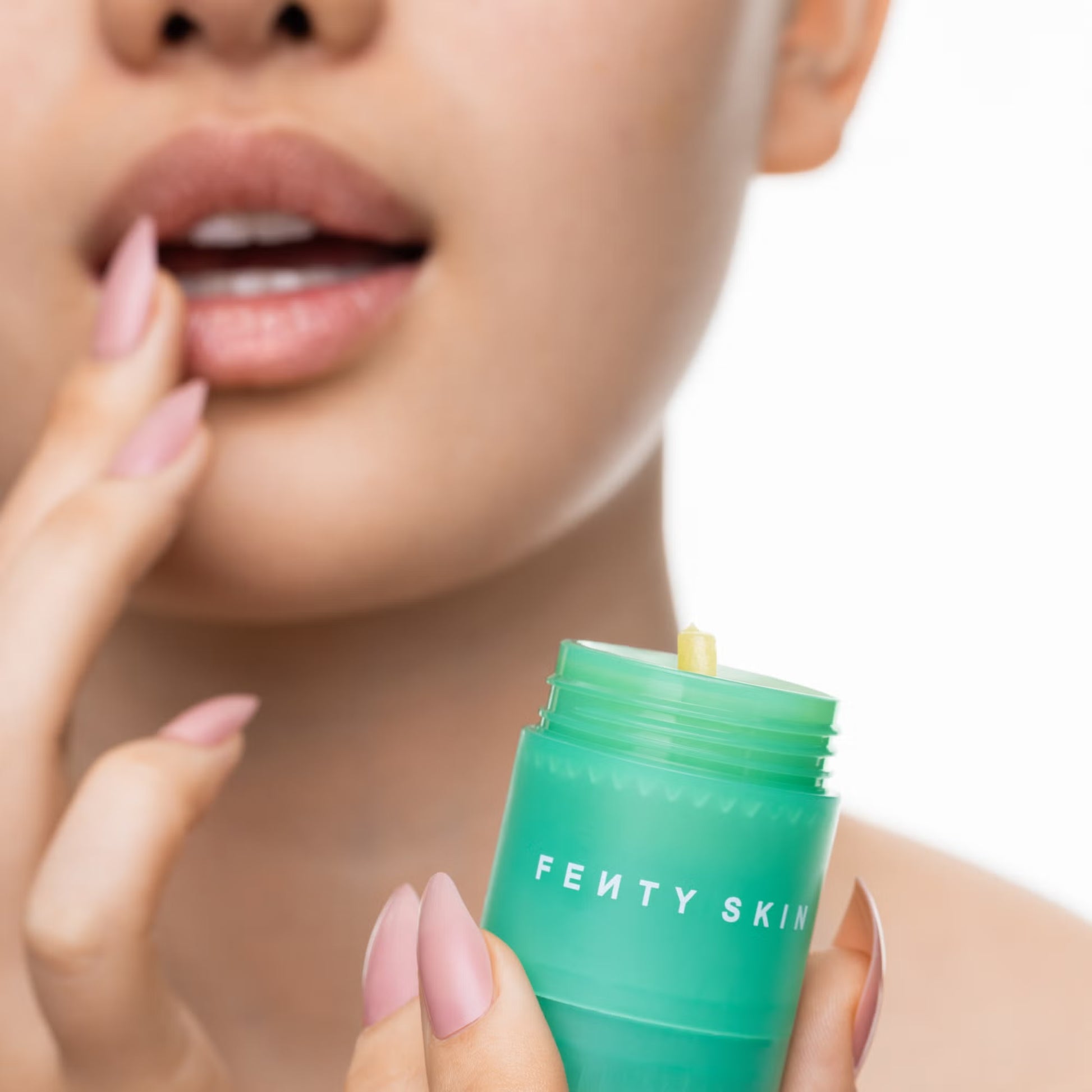 Person holding a green Fenty Skin product close to their face