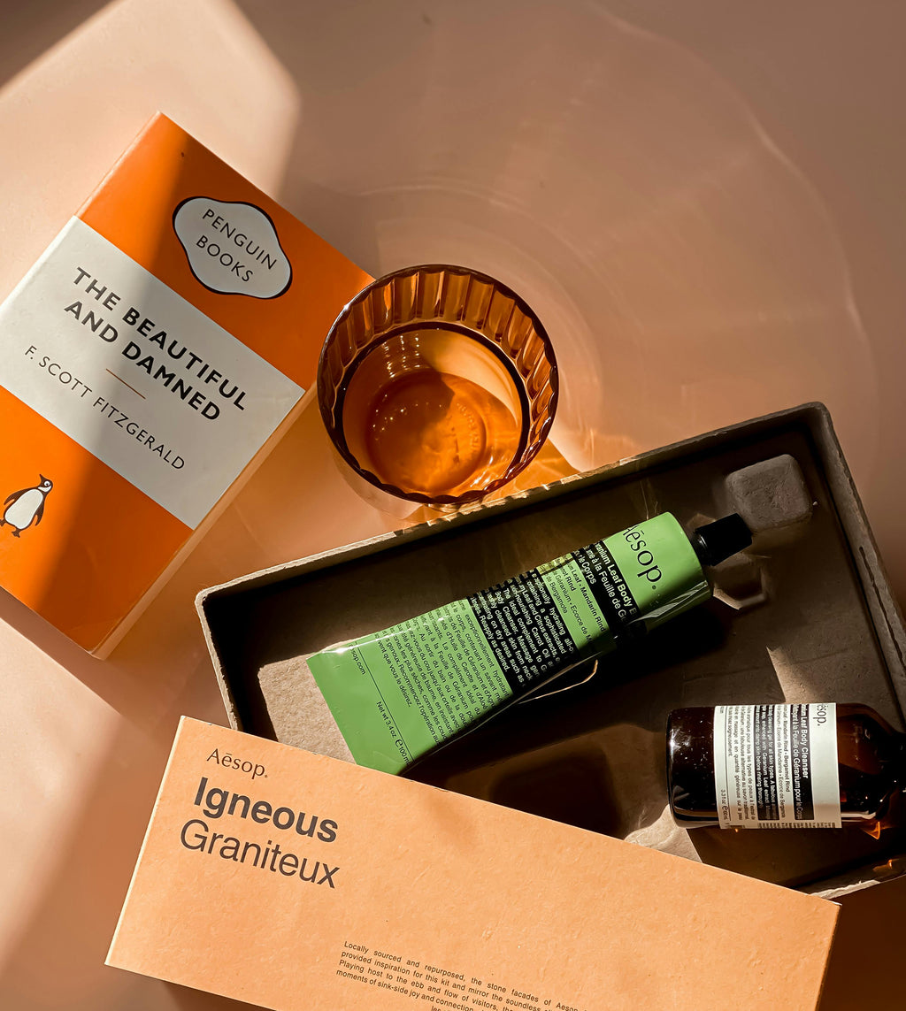 Aesop skincare products and Penguin Books on a textured surface
