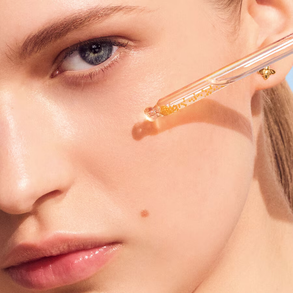 Side-by-side before and after comparison of a woman’s skin showing improved smoothness after 7 days of using Guerlain Abeille Royale Youth Watery Oil Serum, with close-up texture hexagons.
