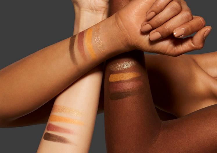 Three arms with makeup swatches on a dark background